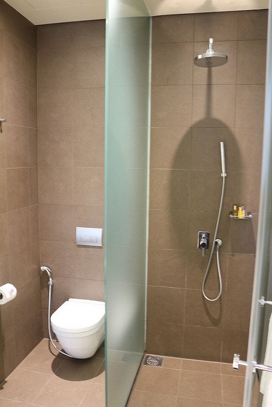 a bathroom with a toilet, shower and glass partition to the wall in front of it