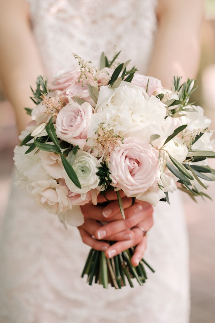 a bride holding a bouquet of white and pink flowers