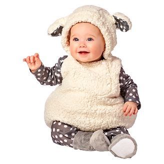 a baby in a sheep costume sitting on the floor with her hands up and smiling