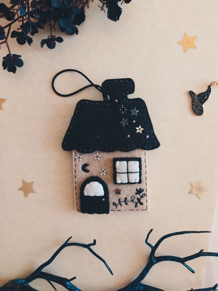 a house shaped ornament hanging on a wall next to some branches and stars