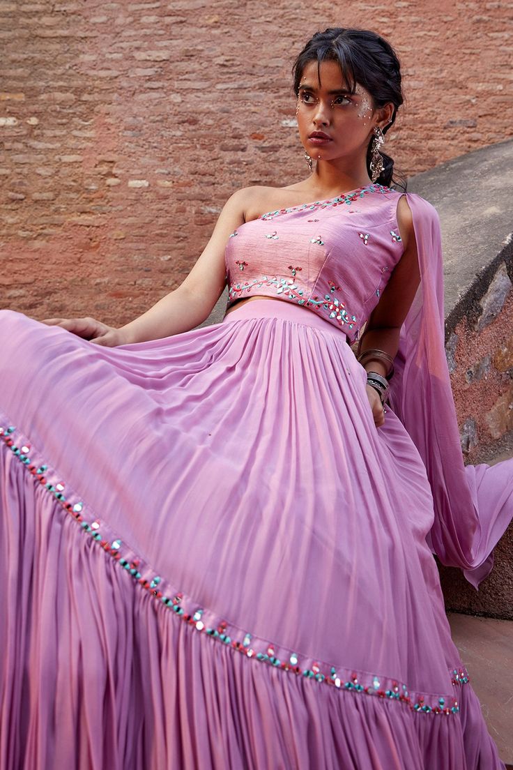 Mauve hand embroidered one shoulder choli with attached drape. Paired with tiered lehenga.
Components:2
Pattern:Hand embroidered
Type of Work:Resham work, Mirror work
Neckline:One shoulder
Sleeve Length:Sleeveless
Fabric:Georgette, Bhagalpuri
Color:Purple
Other Details:
Mirror work detail
Occasion:Party, Reception - Aza Fashions Fitted Pre-draped Saree With Gota Work, Designer Wear Fitted Pre-draped Saree With Gota Work, Designer Fitted Pre-draped Saree With Gota Work, Fitted One-shoulder Party Sets, Party Wear Dresses With Gota Work In Traditional Drape, One-shoulder Bollywood Dress With Zari Work, One Shoulder Bollywood Dress With Zari Work, One Shoulder Dress With Zari Work For Designer Wear, Bollywood One Shoulder Dress With Zari Work