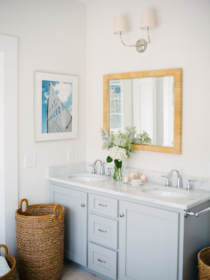 a bathroom with two sinks, mirrors and baskets on the floor in front of it