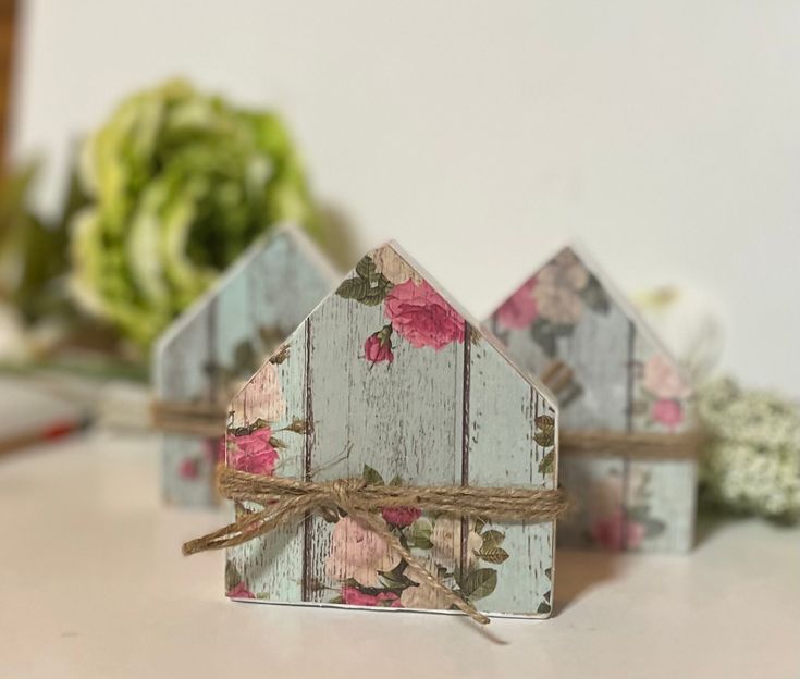 small wooden houses with flowers on them are tied to twine and placed next to each other