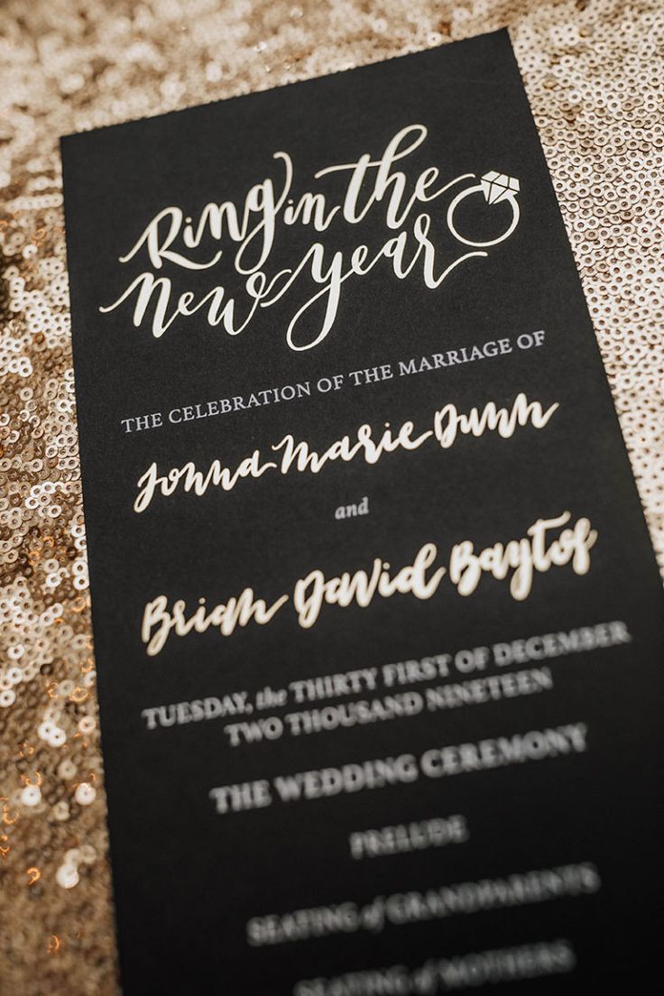 a black and white wedding card with gold glitters on the bottom, in front of a sequin tablecloth