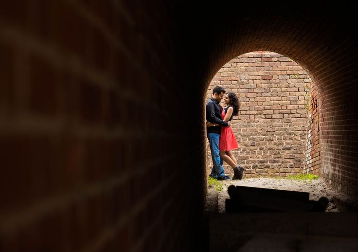 a man and woman are standing in an archway with their arms around each other as they look into the distance