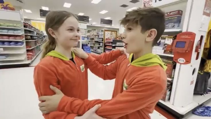 two young children standing in front of a store display looking at each other and smiling