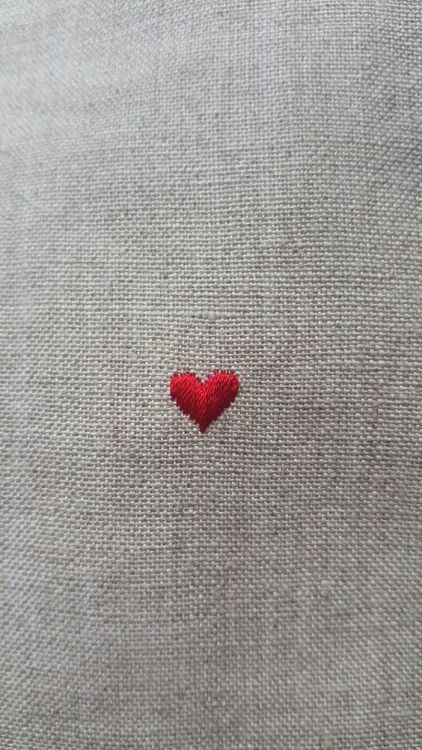 a red heart is embroidered on the back of a gray shirt that has been worn by someone