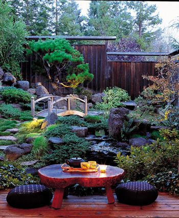 an outdoor garden with rocks, plants and water features in the background is a bridge