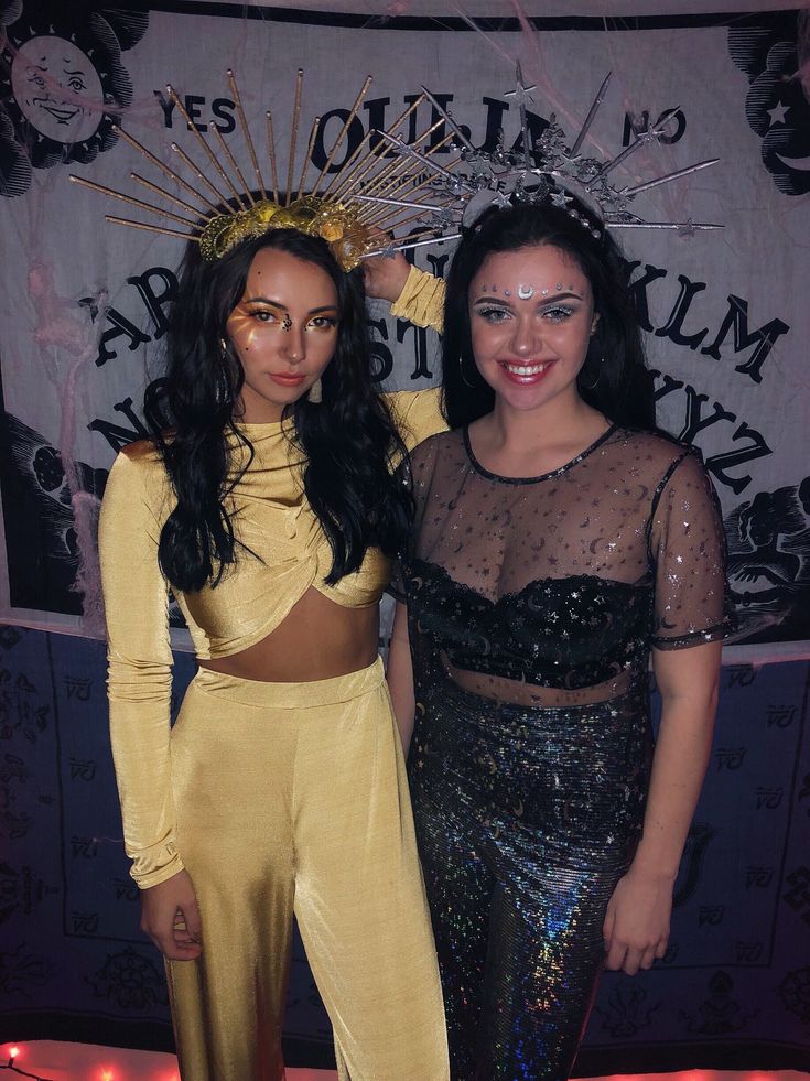 two women standing next to each other in front of a wall with lights on it