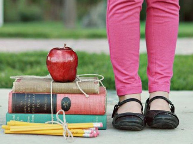 a stack of books with an apple sitting on top of them next to a pair of shoes