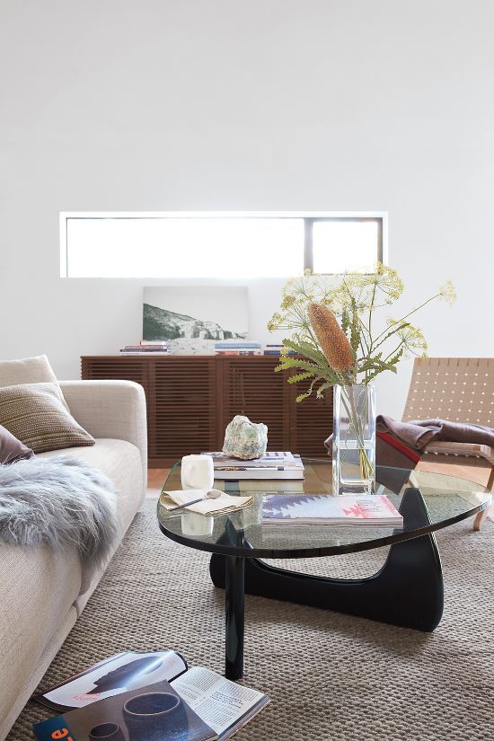 a living room filled with furniture and a glass coffee table on top of a rug