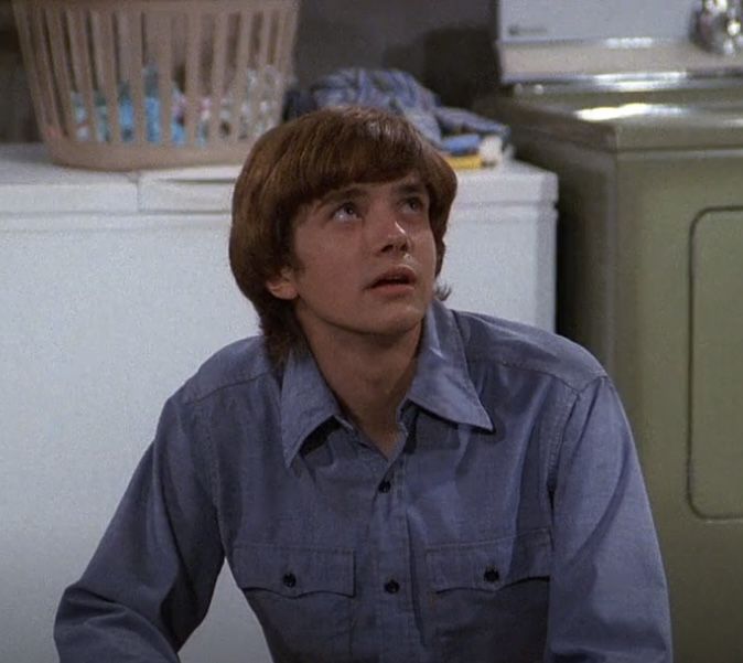 the young man is sitting in front of his washer and looking up at something