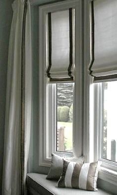 a cat sitting on a window sill in front of two windows with blinds open