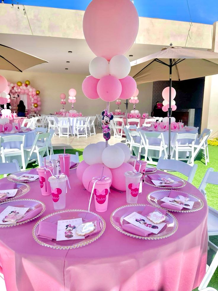 pink and white table setting with balloons, plates and napkins on the table for a baby shower