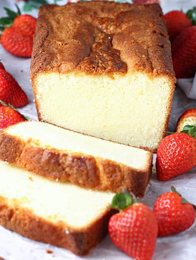 sliced loaf of pound cake with strawberries on the side