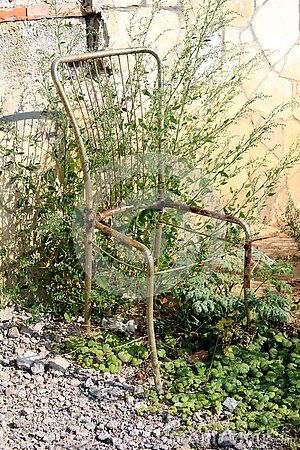 an old rusty chair sitting in the gravel