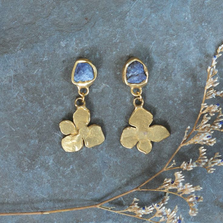 The Arcadia collection was inspired by the succession of spring. As the frost melts away revealing the first buds, it's time to reawaken and rejoice. A time to step into the sunshine and let the sun kiss your face. Tanzanite are embedded in brass with sterling silver earring posts to create these simple and sweet everyday earrings. 1 3/4” Length This piece is handmade-to-order. Each piece will vary slightly due to the uniqueness of the stones. All metal is nickel free. Material: brass, metal, se Gold Natural Stones Earrings Nature-inspired, Gold Nature-inspired Earrings With Natural Stones, Nature-inspired Gold Earrings With Natural Stones, Nature-inspired Hammered Earrings As Gift, Gold Nature-inspired Hand Forged Earrings, Nature-inspired Hand Forged Gold Earrings, Nature-inspired Yellow Gold Brass Jewelry, Nature-inspired Hand Forged Drop Earrings, Hand Forged Nature-inspired Drop Earrings