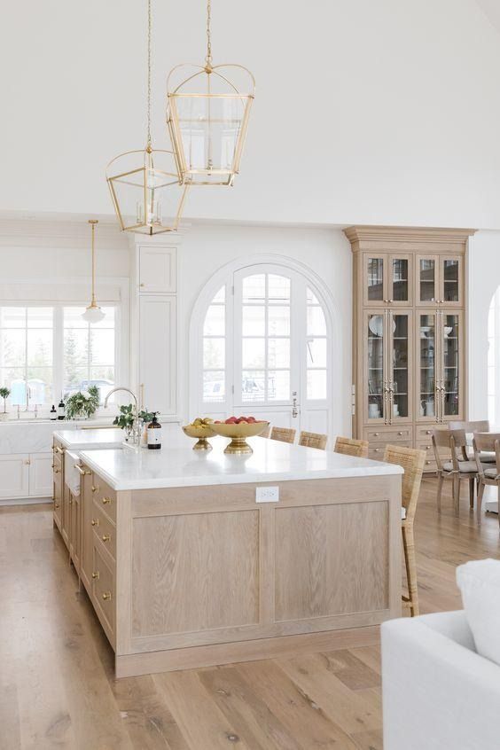 a large open concept kitchen with white walls and wood flooring that has an island in the center