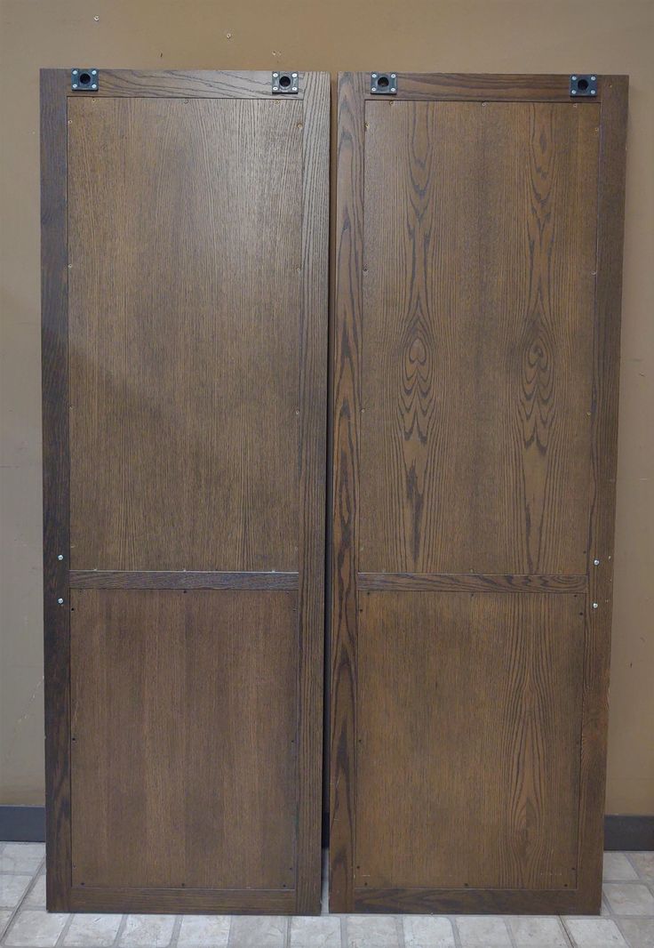 two brown wooden doors sitting next to each other on top of a tiled floor in front of a wall