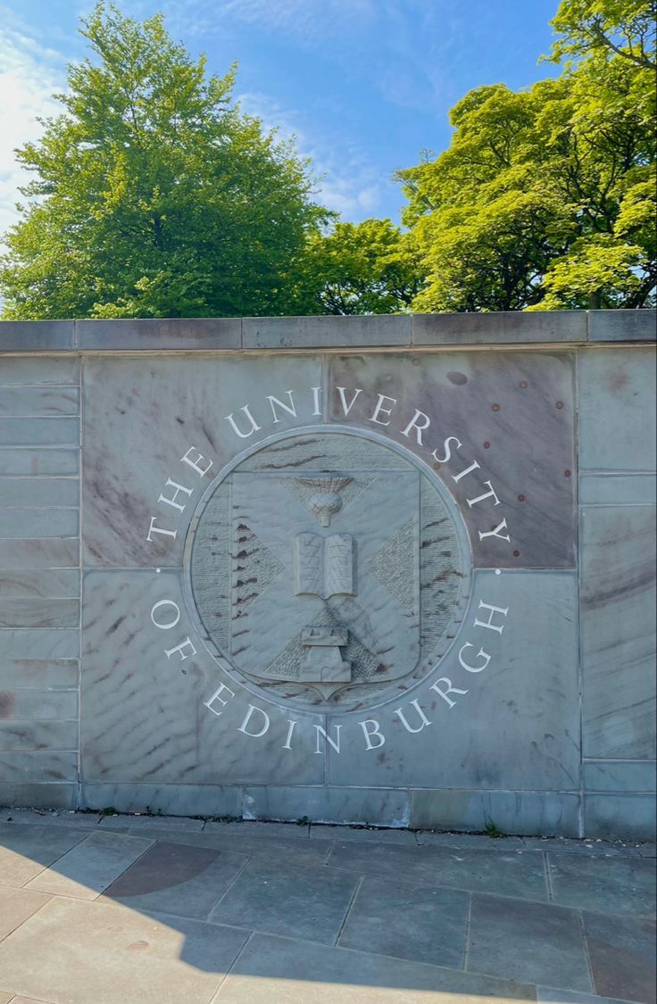 the university of edinburgh sign is shown in front of some trees and bushes on a sunny day