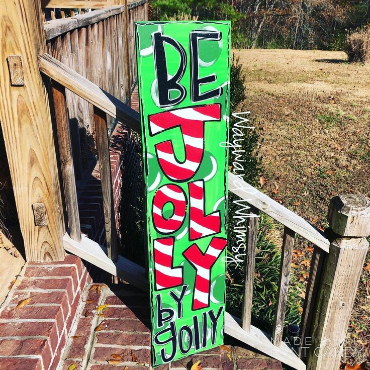 a green sign that says be merry on the side of a wooden fence next to a brick walkway