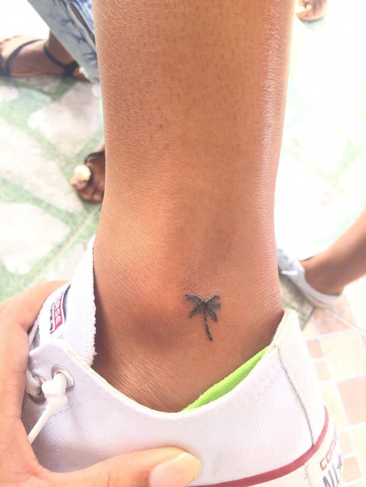 a person with a small tattoo on their ankle that has a palm tree on it