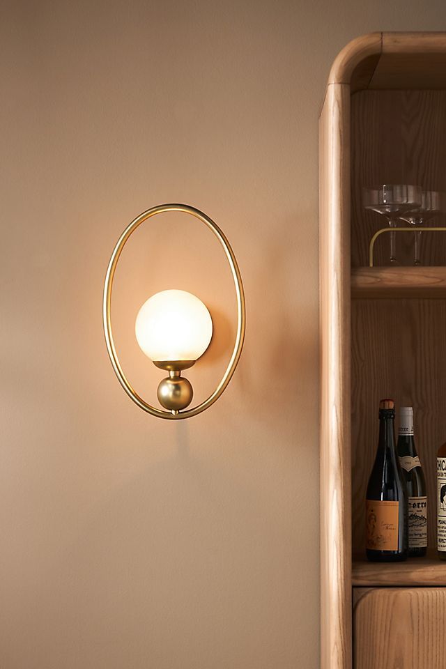 a light that is on the side of a wall next to bottles and wine glasses