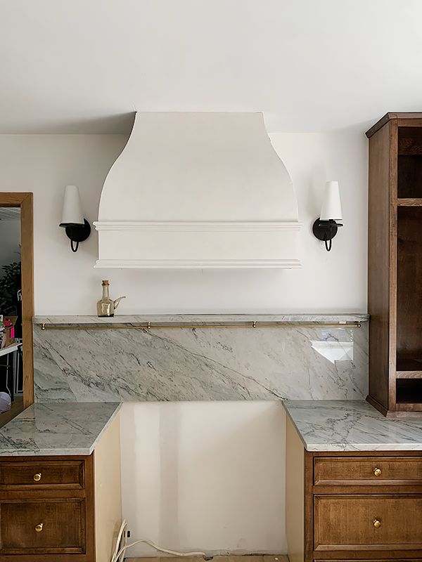 a kitchen with marble counter tops and wooden cabinetry, along with an oven hood