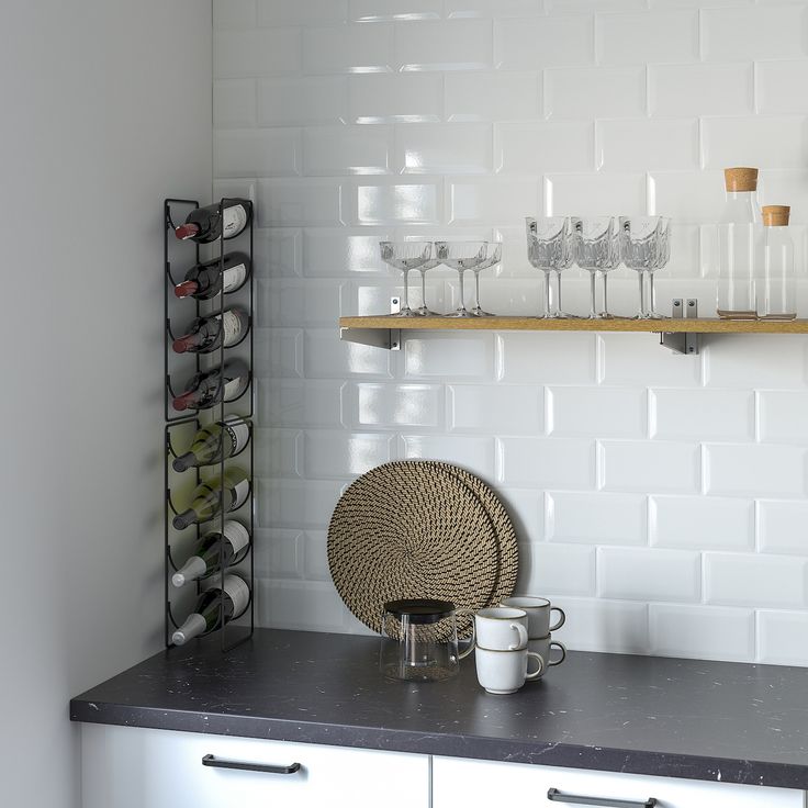 a kitchen counter with wine glasses and cups on the top shelf, next to a wall mounted shelving unit