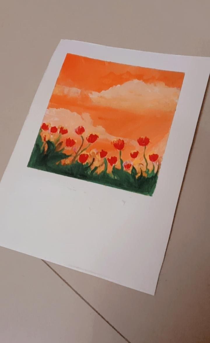 an orange sky with red flowers in the foreground and green grass on the other side