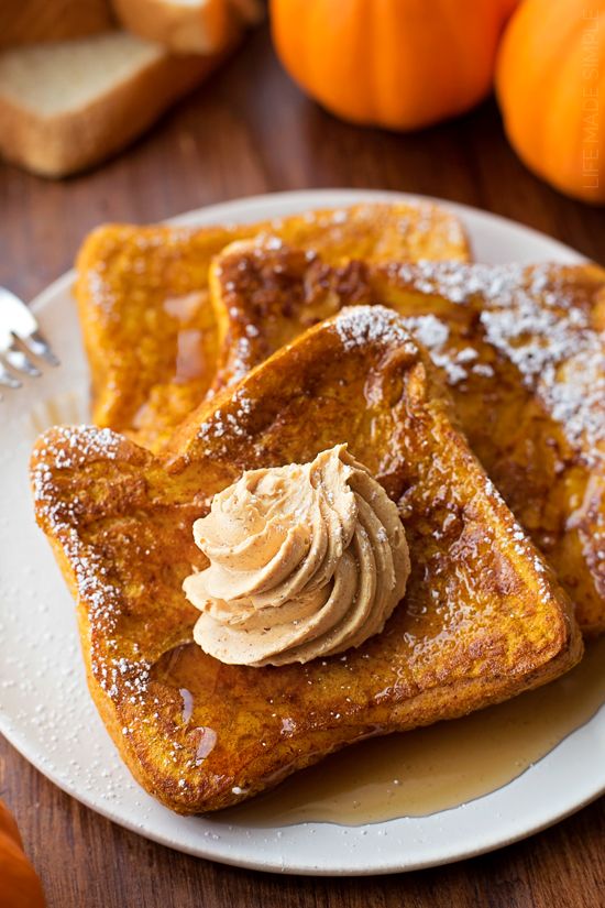 two pieces of french toast on a plate with butter and pumpkins in the background