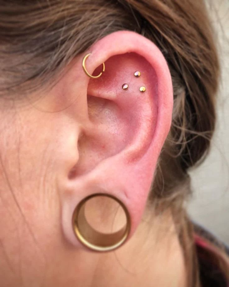 a close up of a person with ear piercings on their ears and behind the ear