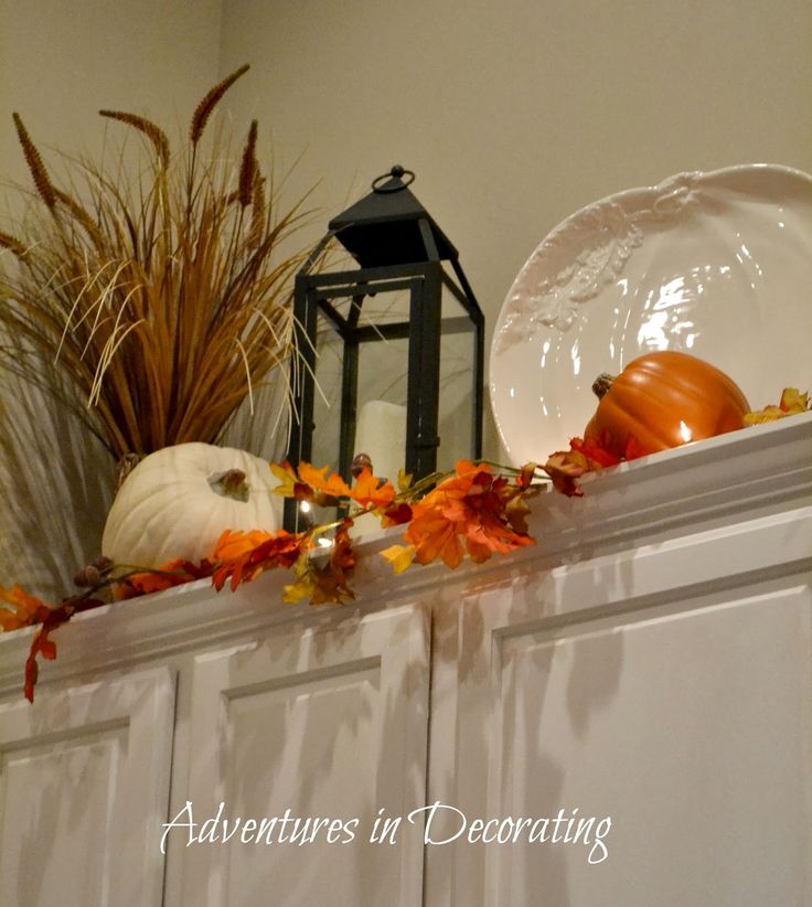 an arrangement of fall decorations on top of a cabinet