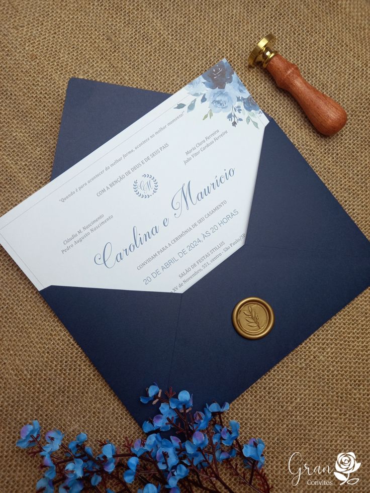 an envelope with a wax stamp on it next to some blue flowers and a bottle opener