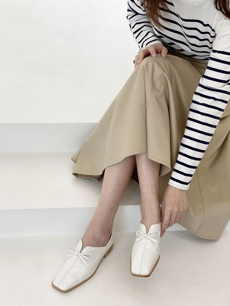 a woman sitting on the ground wearing white shoes