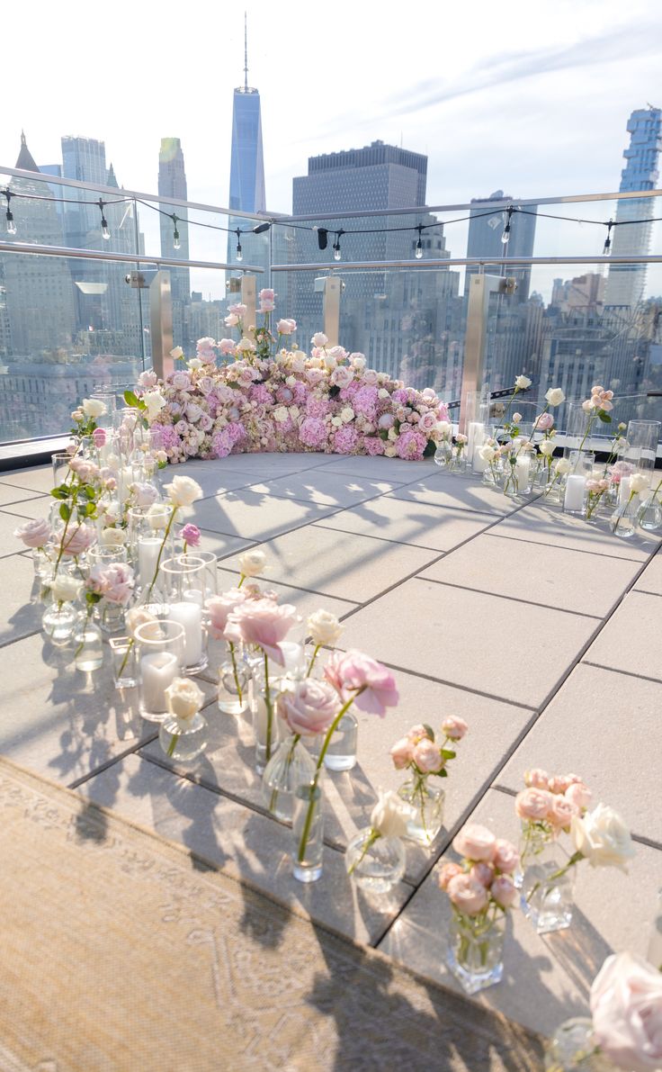 flowers are arranged in vases on the roof of a building with skyscrapers in the background