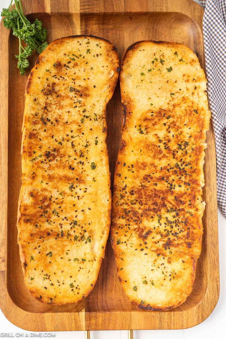 two pieces of bread on a cutting board with parsley sprig next to it