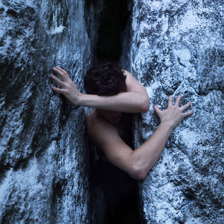 a woman climbing up the side of a mountain with her hands on it's face