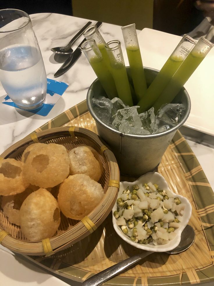 some food is sitting on a tray with ice water and silverware next to it