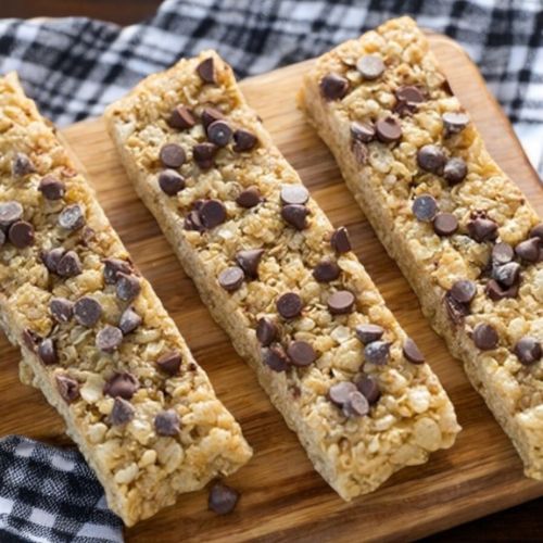 three pieces of granola bar on a wooden cutting board