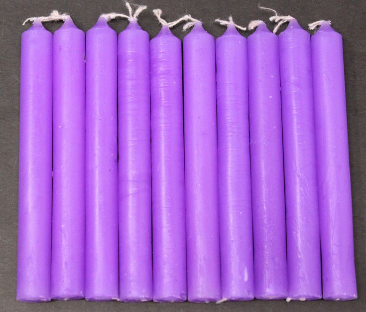 six purple candles are lined up in a row on the floor with twine string