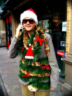 a man in a santa hat is talking on his cell phone while wearing a christmas wreath