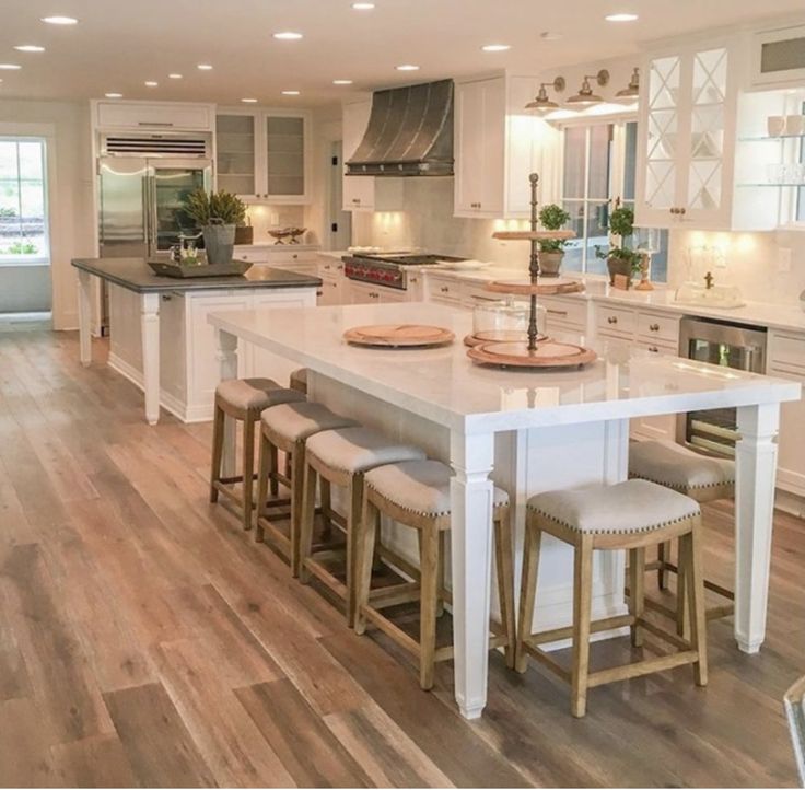 a large kitchen with white cabinets and wooden floors