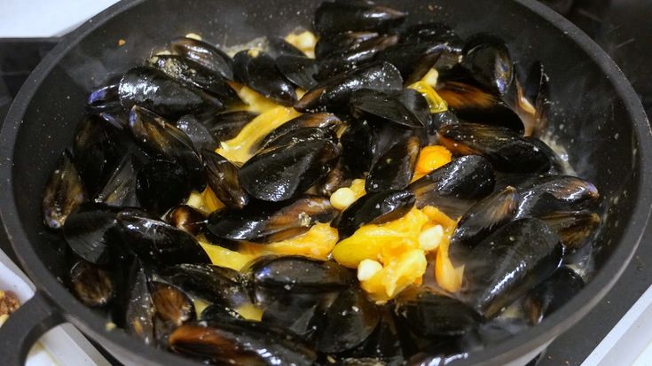 mussels are being cooked in a skillet on the stove