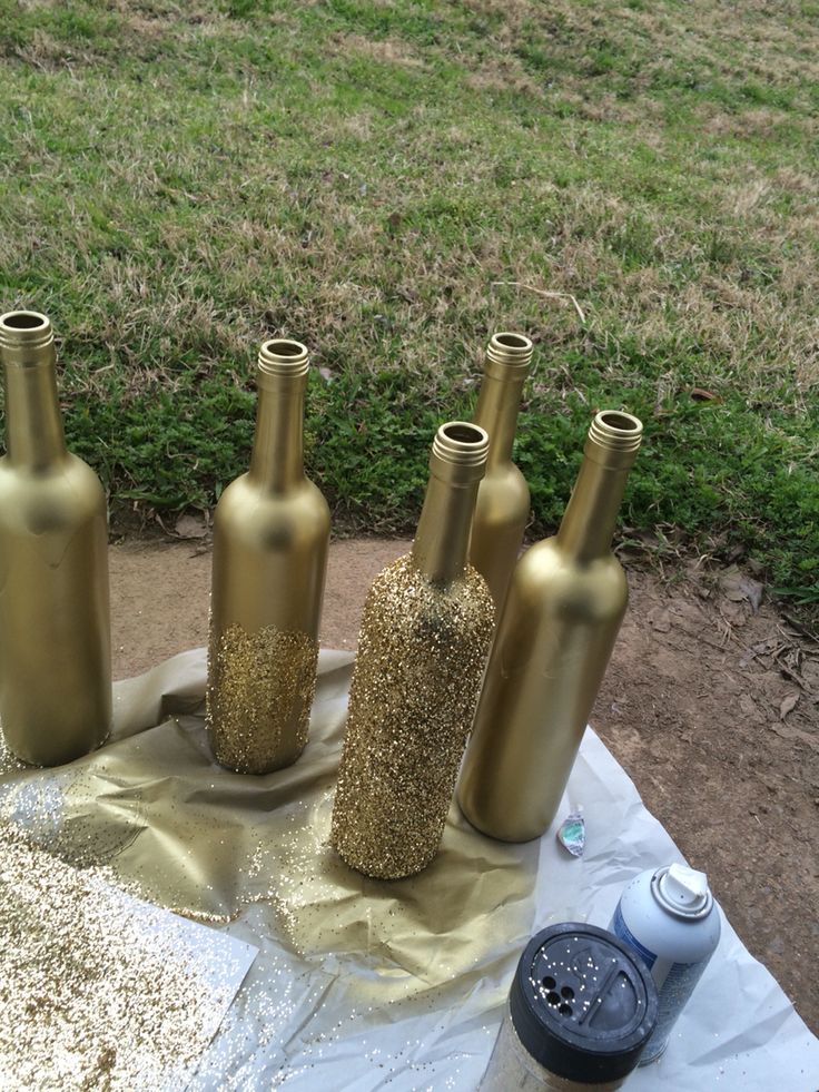 five gold vases sitting on top of a table covered in sand next to a green field