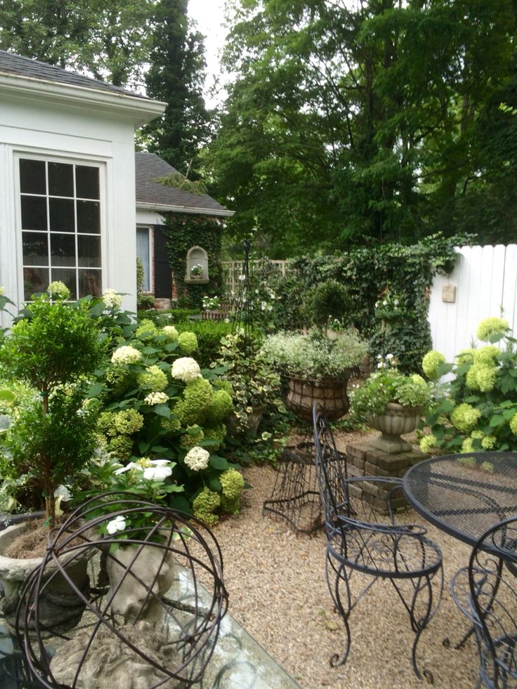 an outdoor patio with tables and chairs in the middle of it, surrounded by greenery