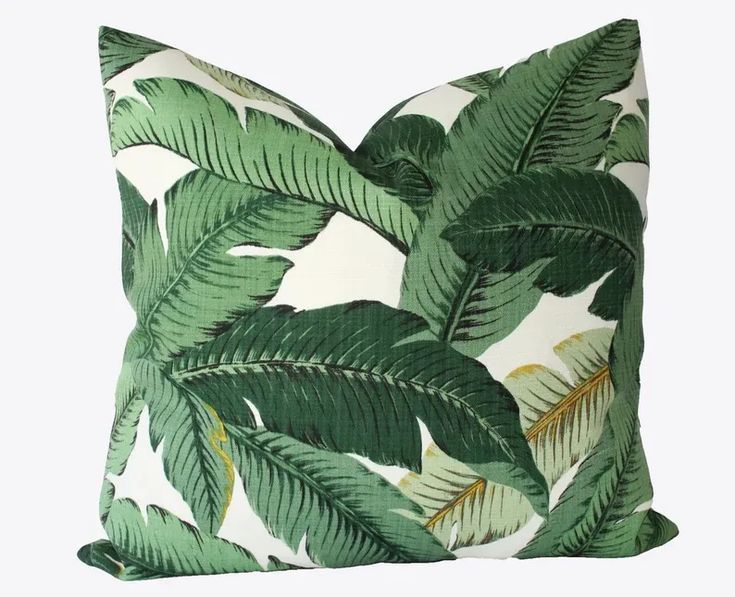 a green and white pillow with palm leaf print on it's side, against a white background