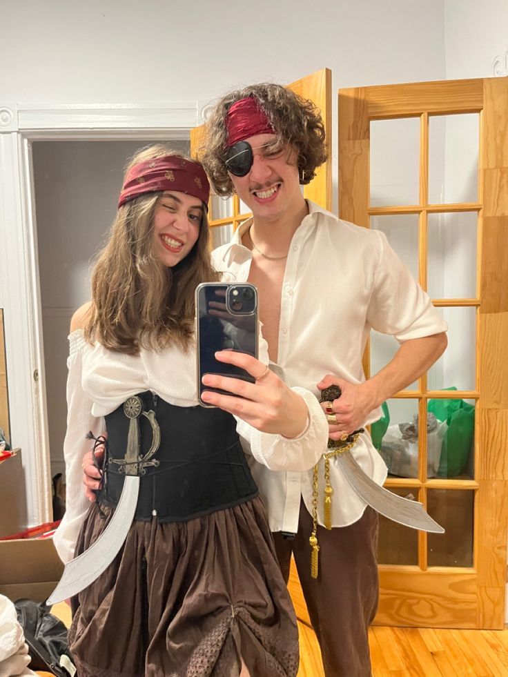 a man and woman in pirate costumes taking a selfie