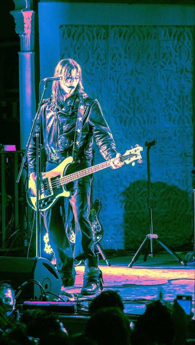 a man standing on top of a stage holding a guitar