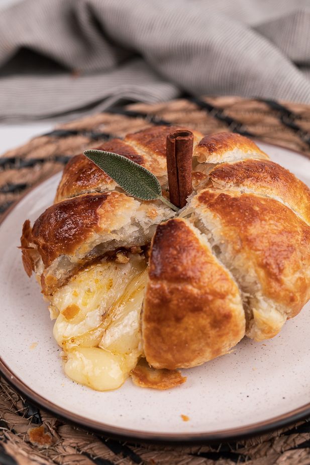 a croissant on a plate with an olive sprig